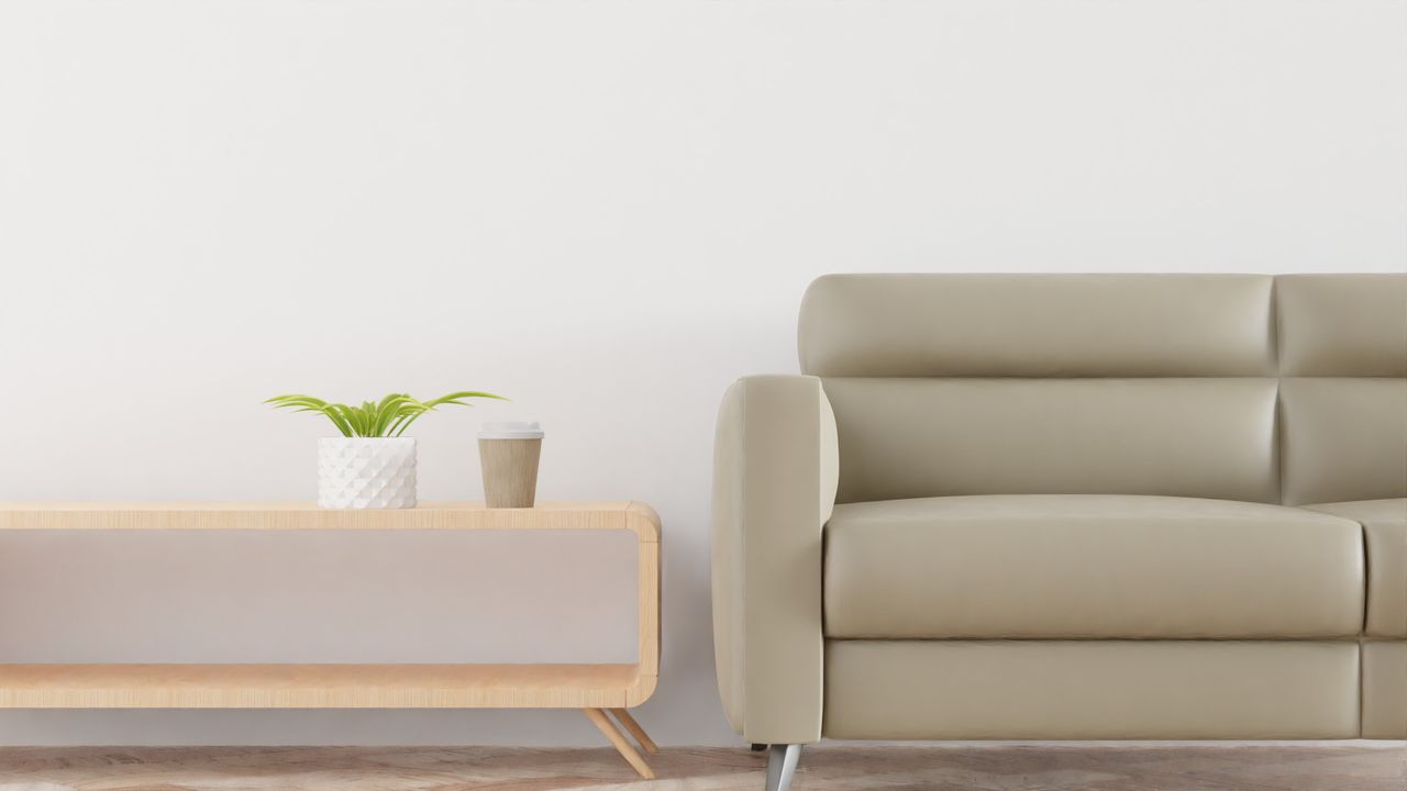 Modern living room with a beige sofa, plant, and coffee cup on a stylish wooden table.