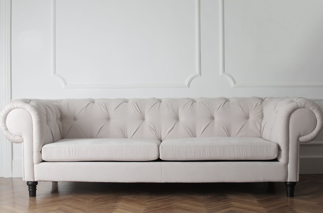 Luxurious white sofa in a modern minimalist interior with wooden flooring.