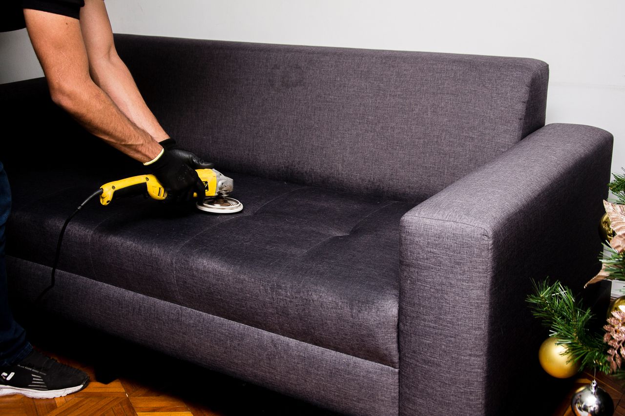 A professional performs sofa cleaning with a grinder in an indoor setting, showcasing efficient service.