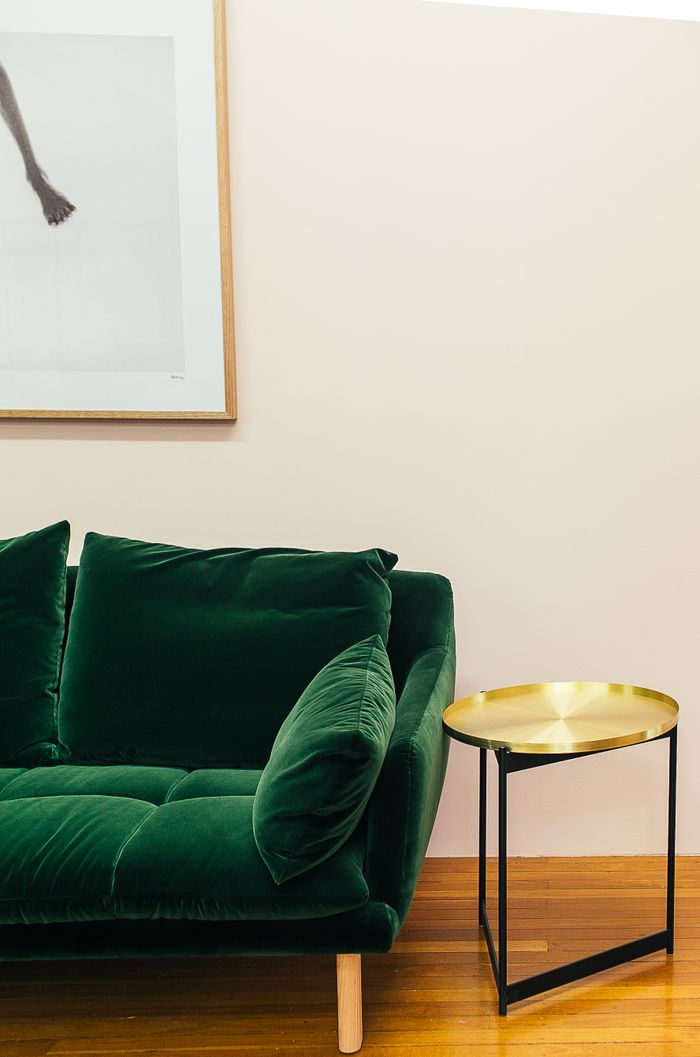 Soft comfortable green velour couch with cushions placed near small round table in stylish living room