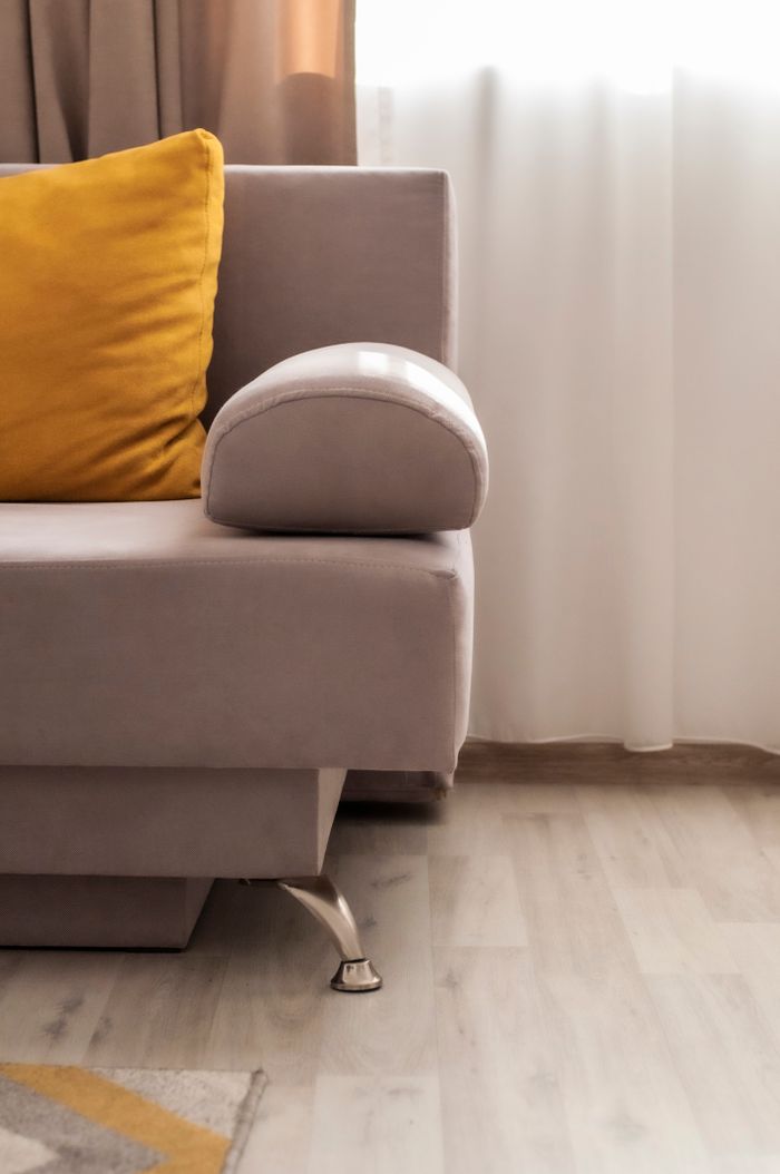 A stylish indoor setting featuring a modern beige sofa and a vibrant yellow pillow, offering a cozy vibe.