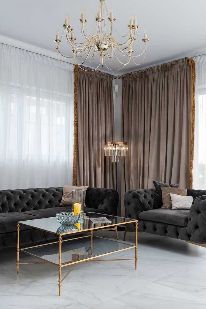 Interior of cozy modern room with comfortable sofas placed at side table and floor lamp near windows with curtains at home